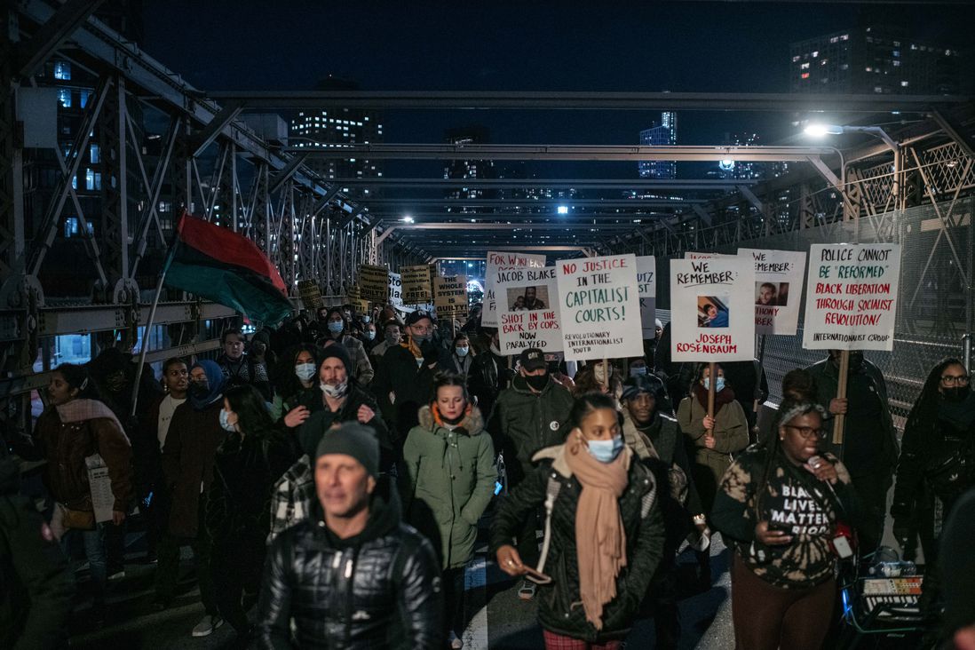 Protesters on the Brooklyn Bridge hold up signs criticizing the justice system during a demonstration against the not guilty verdict for Kyle Rittenhouse.